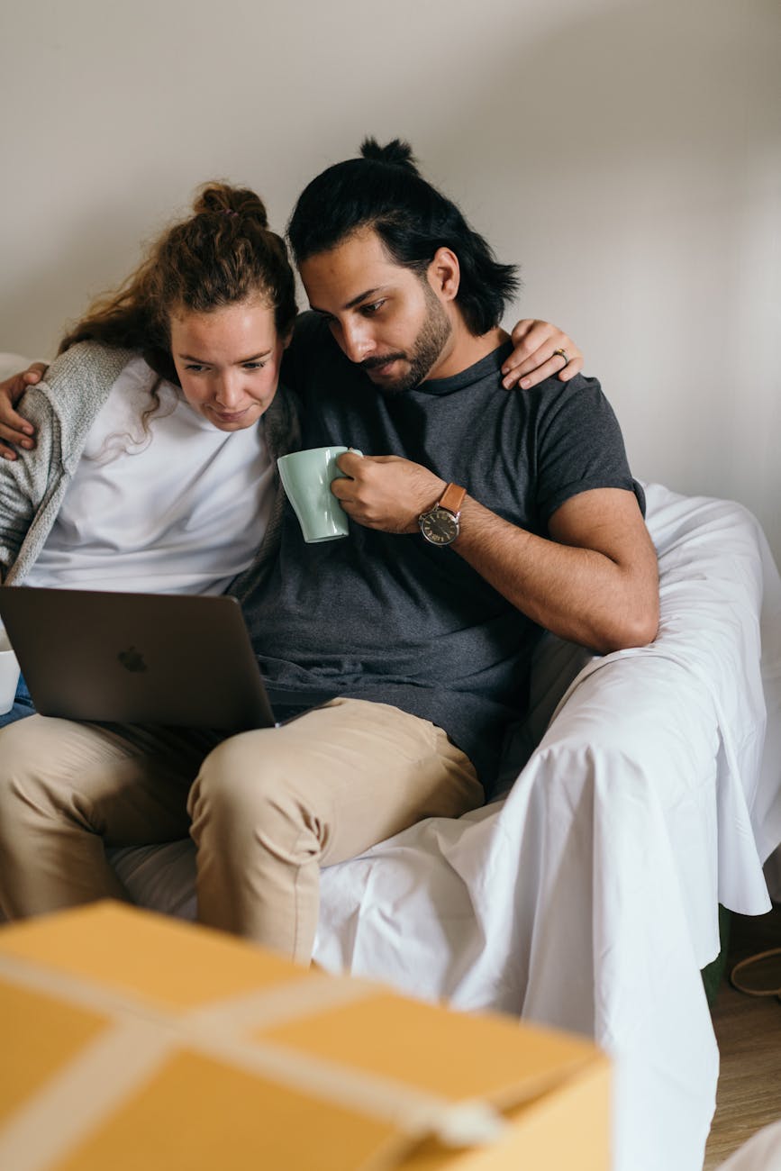 multiethnic couple surfing net on laptop in new house
