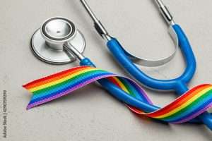 Stethoscope and LGBT rainbow ribbon pride symbol. Medical support after sex reassignment surgery. Grey background.